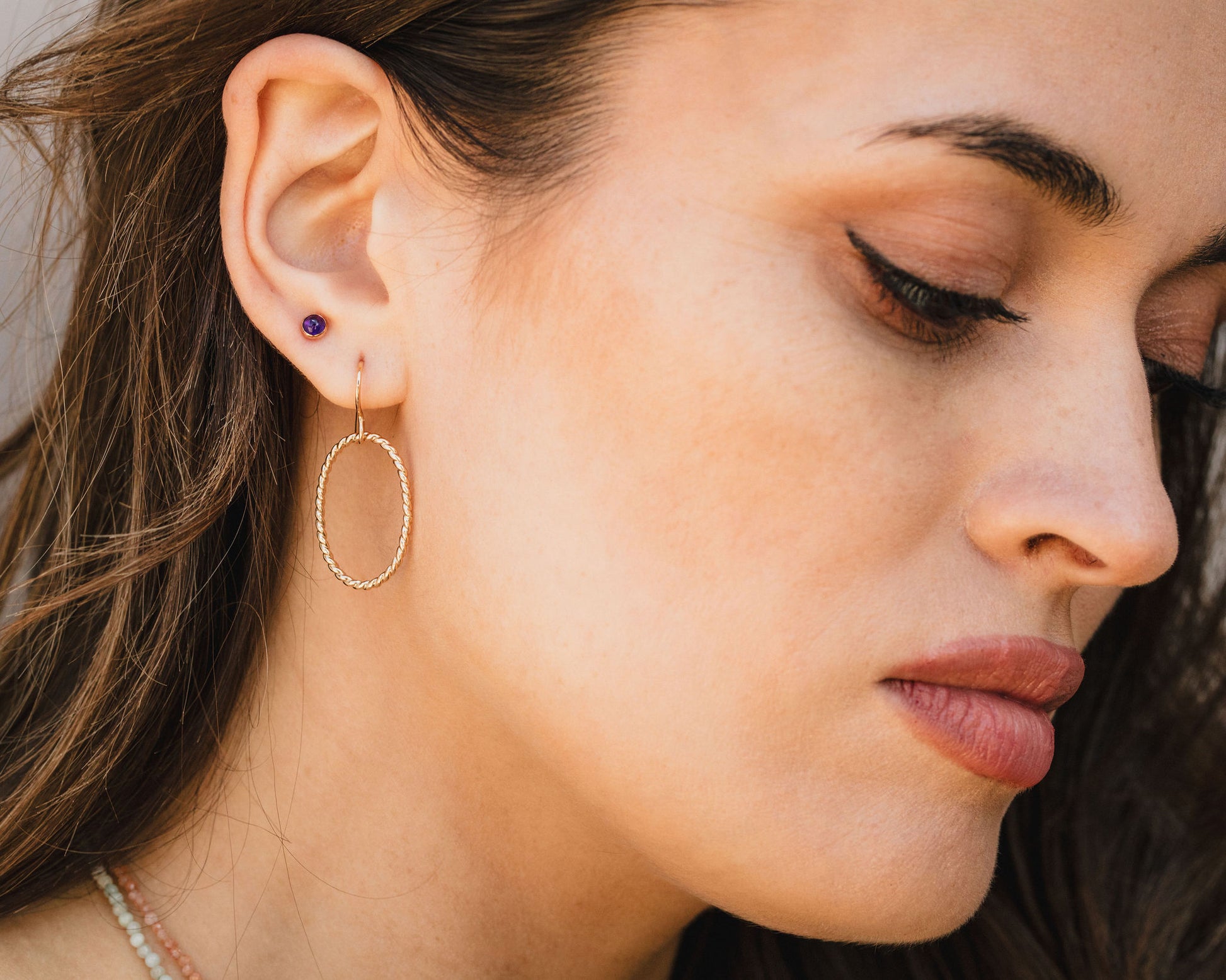 A close-up of a woman's face, focusing on her earrings and lips.
