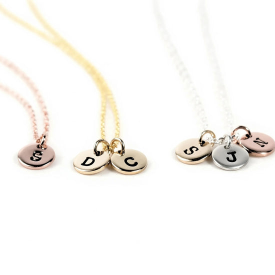 Three necklaces with personalized charms attached, each with a letter engraved on it.