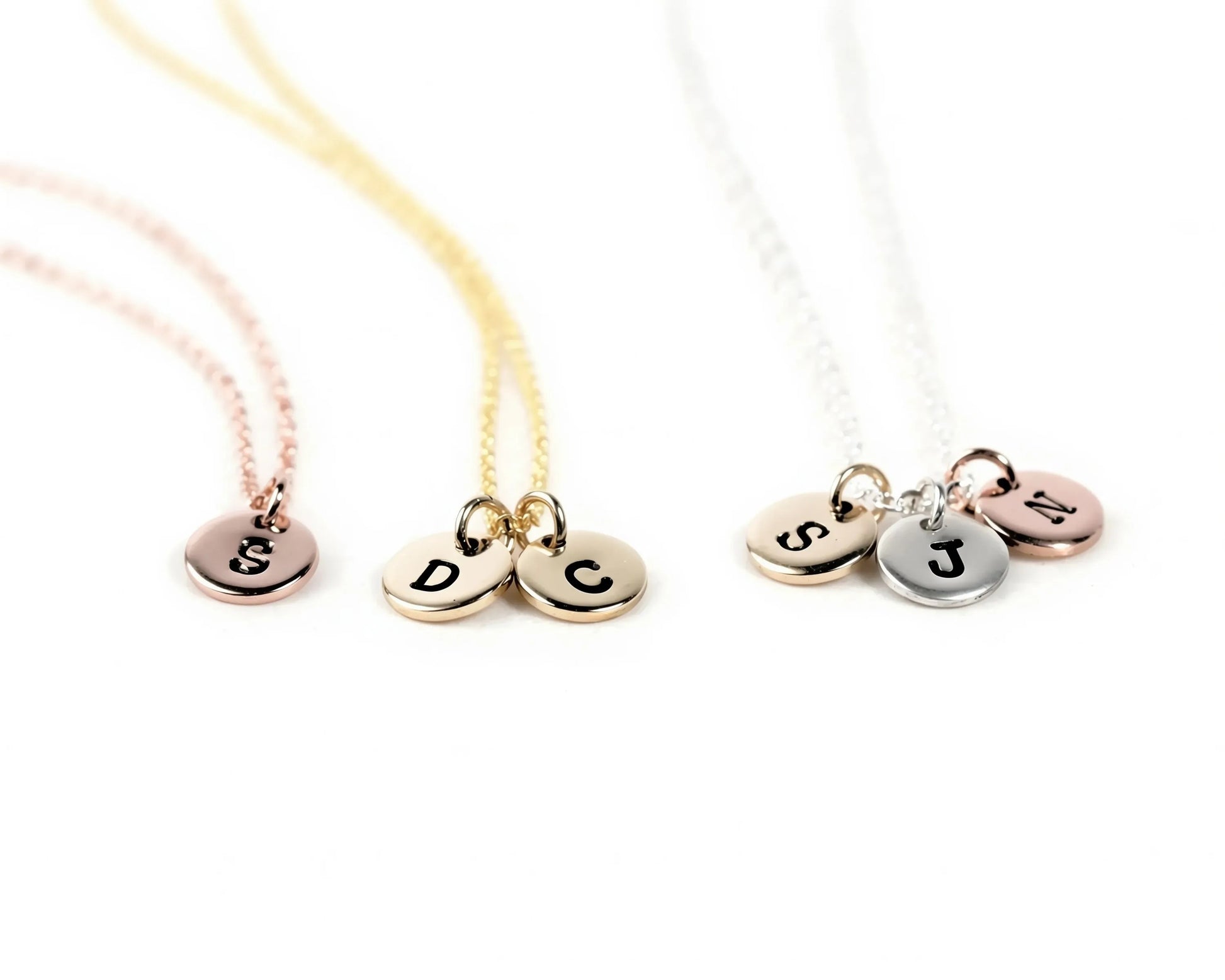 Three necklaces with personalized charms attached, each with a letter engraved on it.