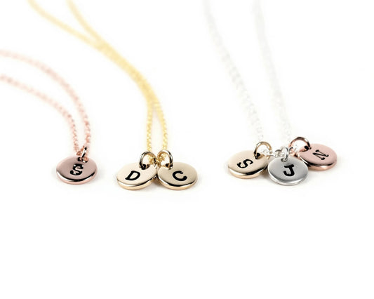 Three necklaces with personalized charms attached, each with a letter engraved on it.