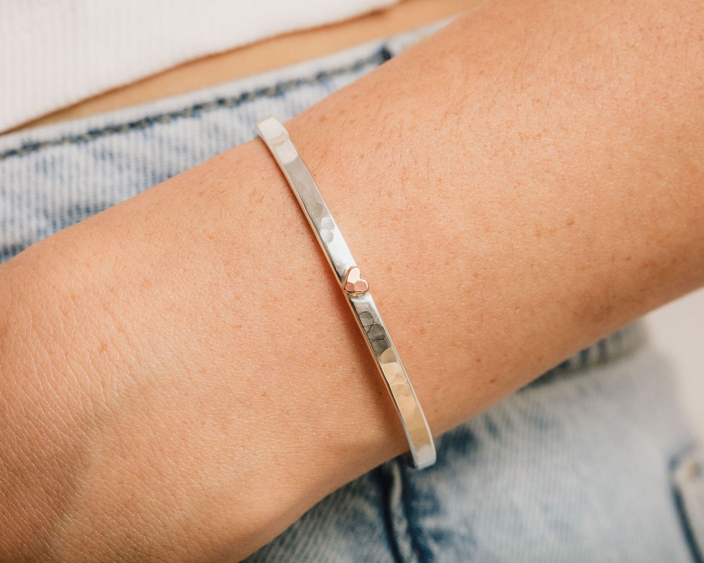 A silver bangle bracelet is worn on a person's wrist.