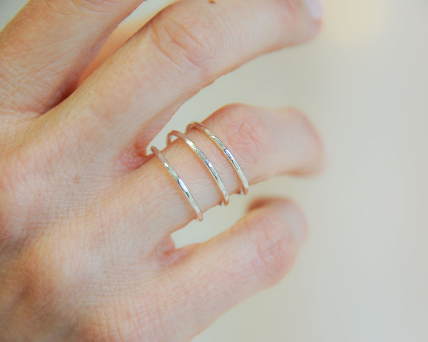 A close-up of a person's hand wearing three stacked rings on the ring finger.