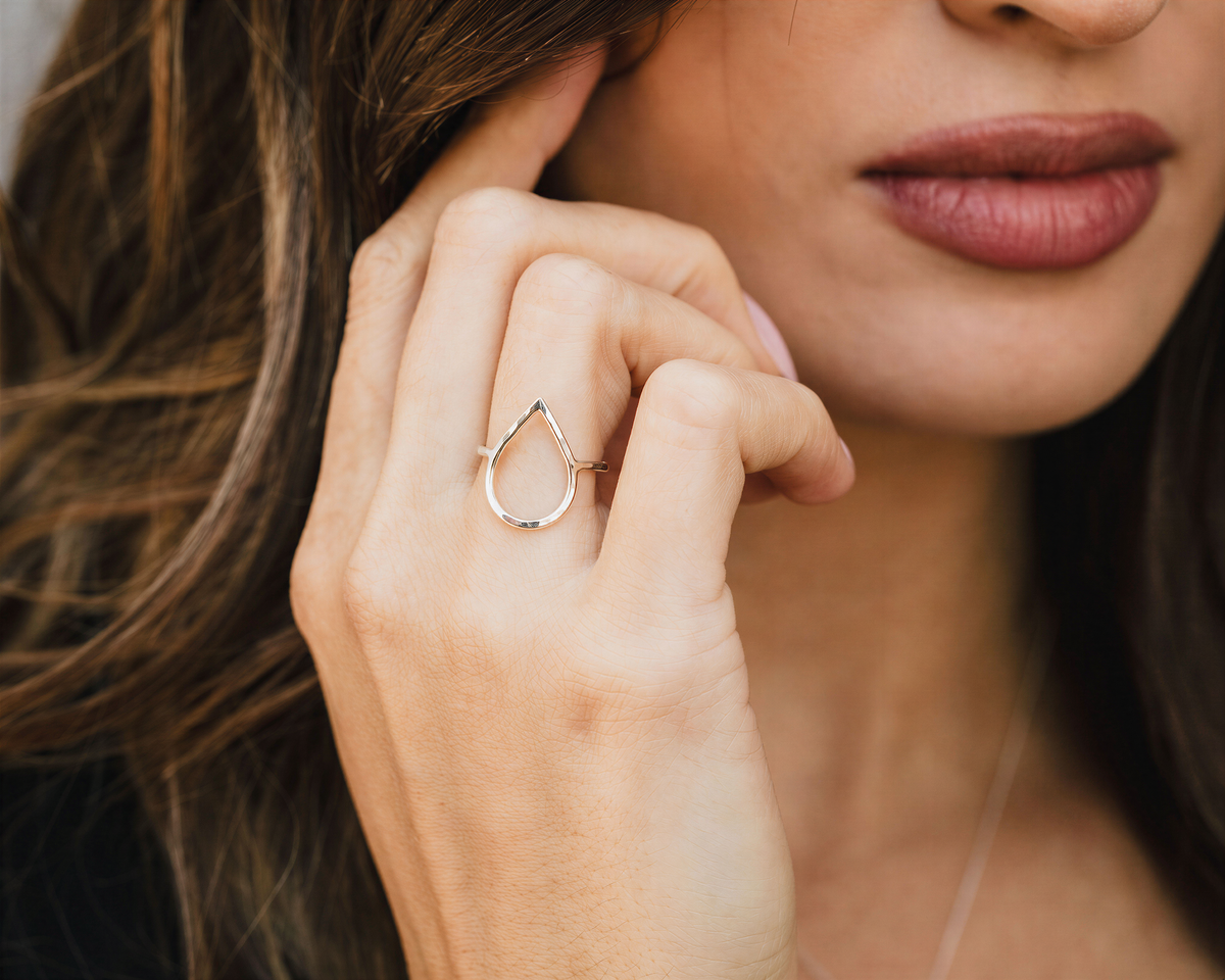 A close-up of a woman's hand wearing a ring, with her hair visible in the background.