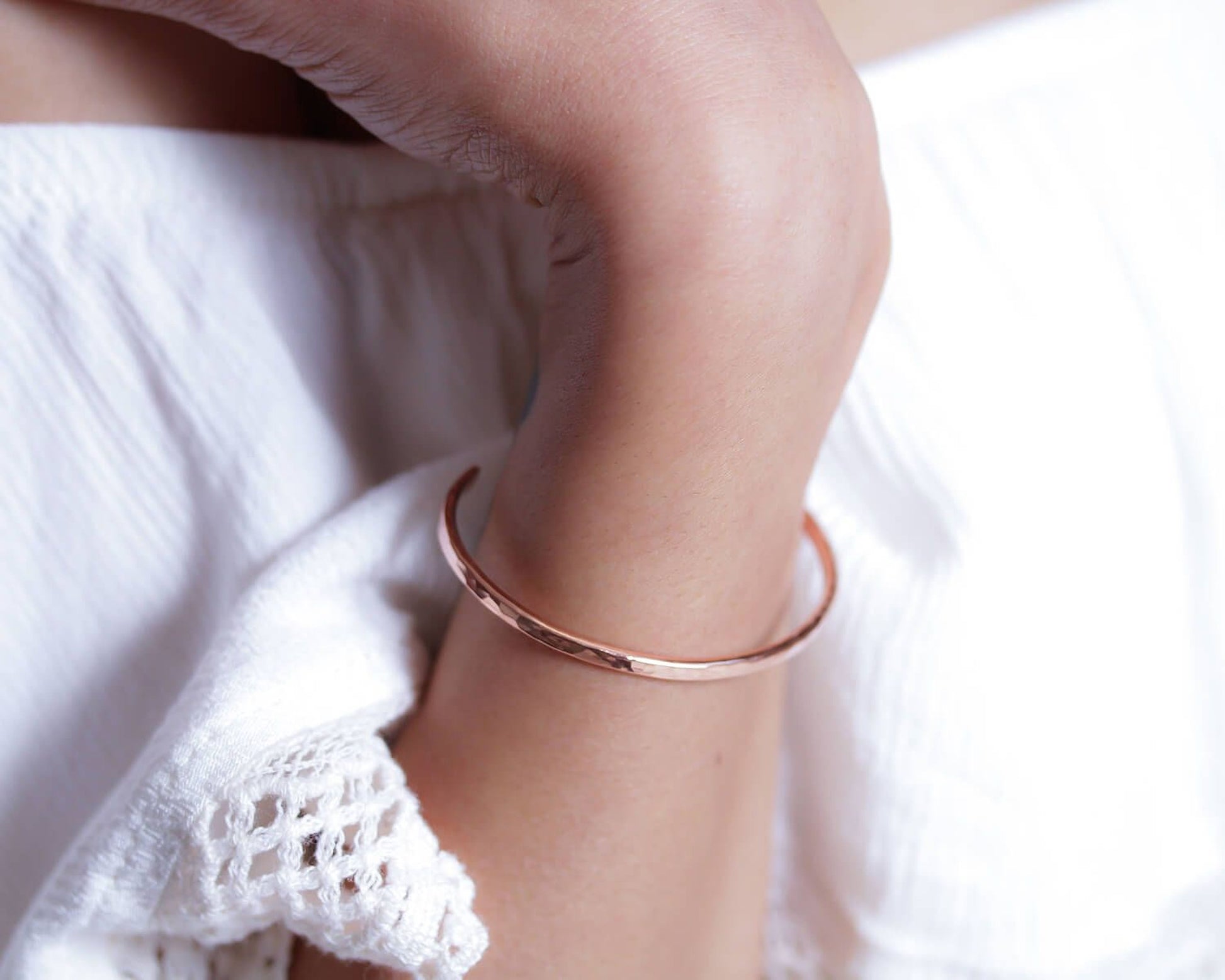A close-up view of a person's arm wearing a copper-colored bracelet.