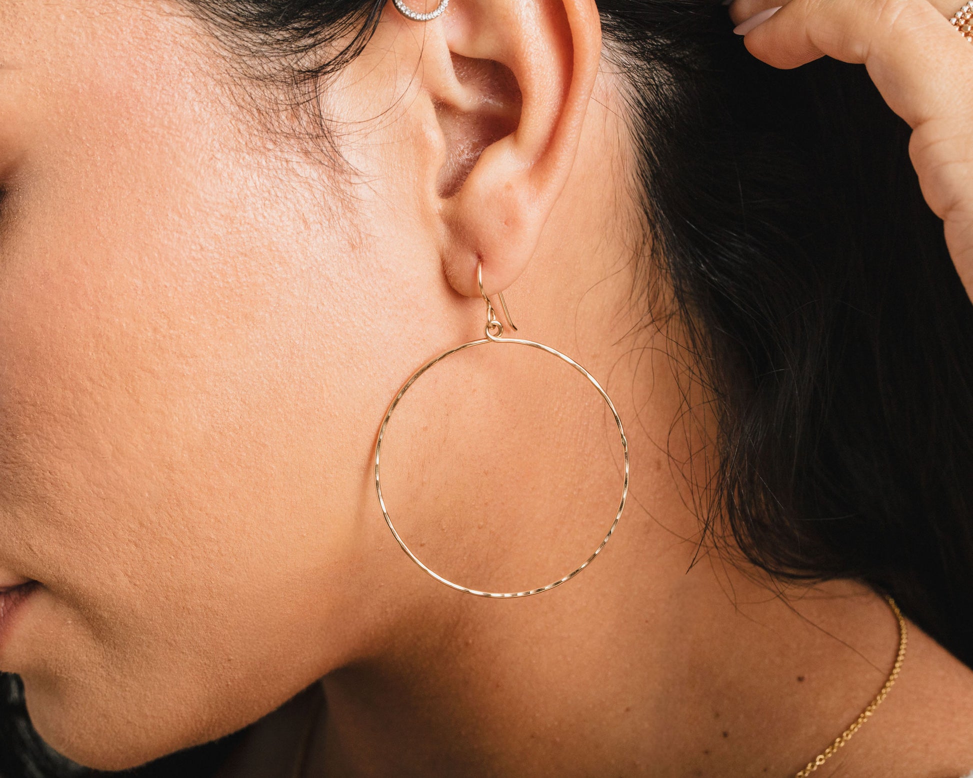 A close-up view of a person's ear adorned with a large hoop earring.