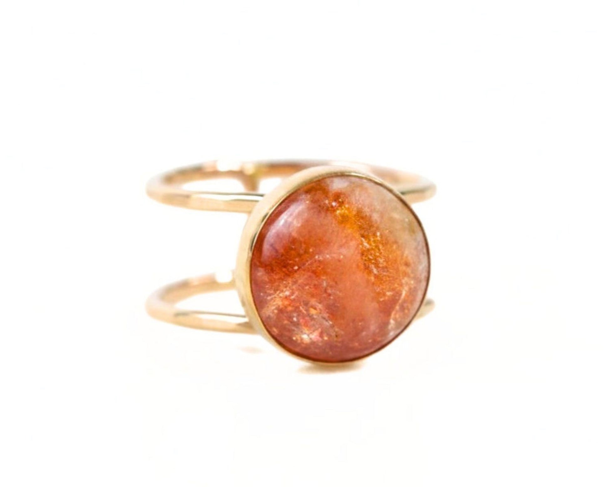 A gold ring with a large, round, orange gemstone set in the center.