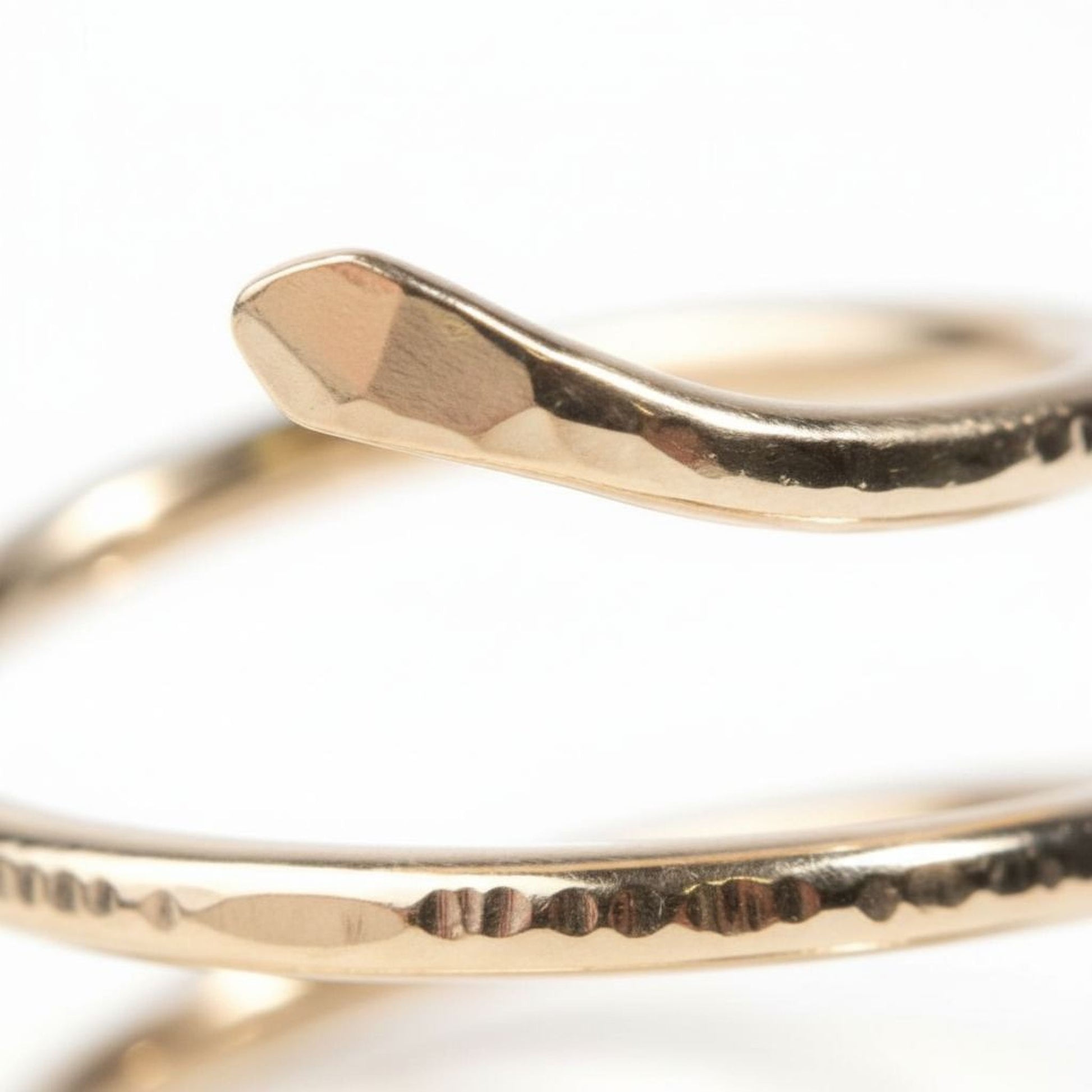 A close-up view of a gold-colored ring with a twisted, spiral-like design.