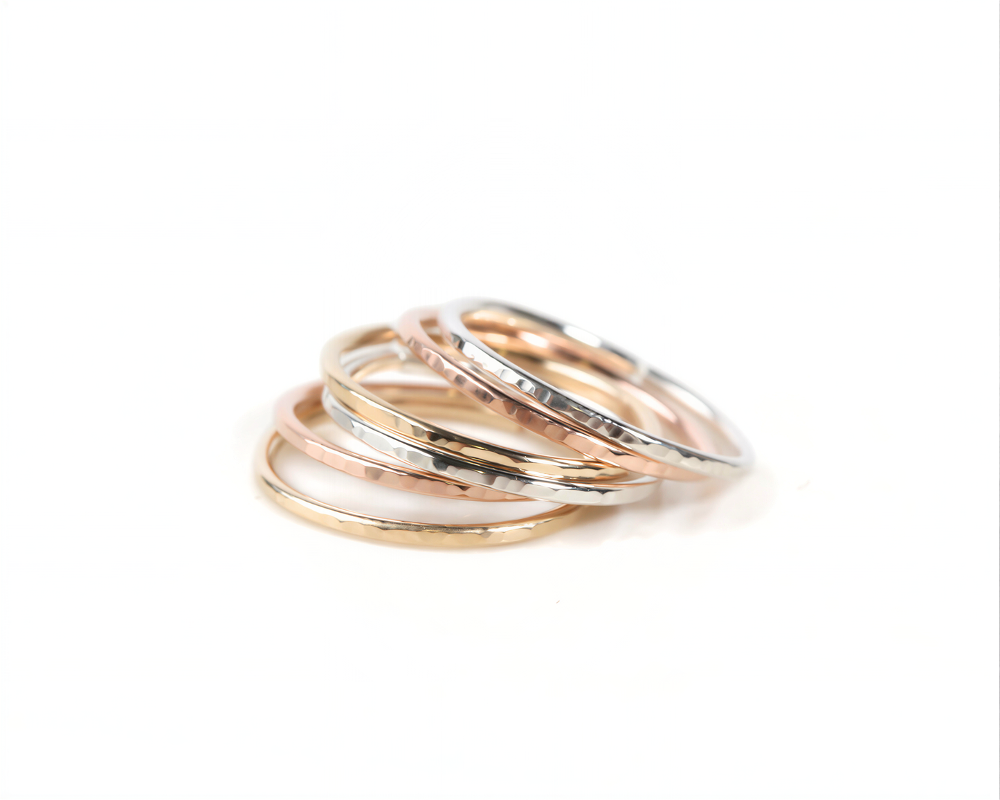 A stack of rings in various colors, including gold, silver, and rose gold, arranged in a visually appealing manner.