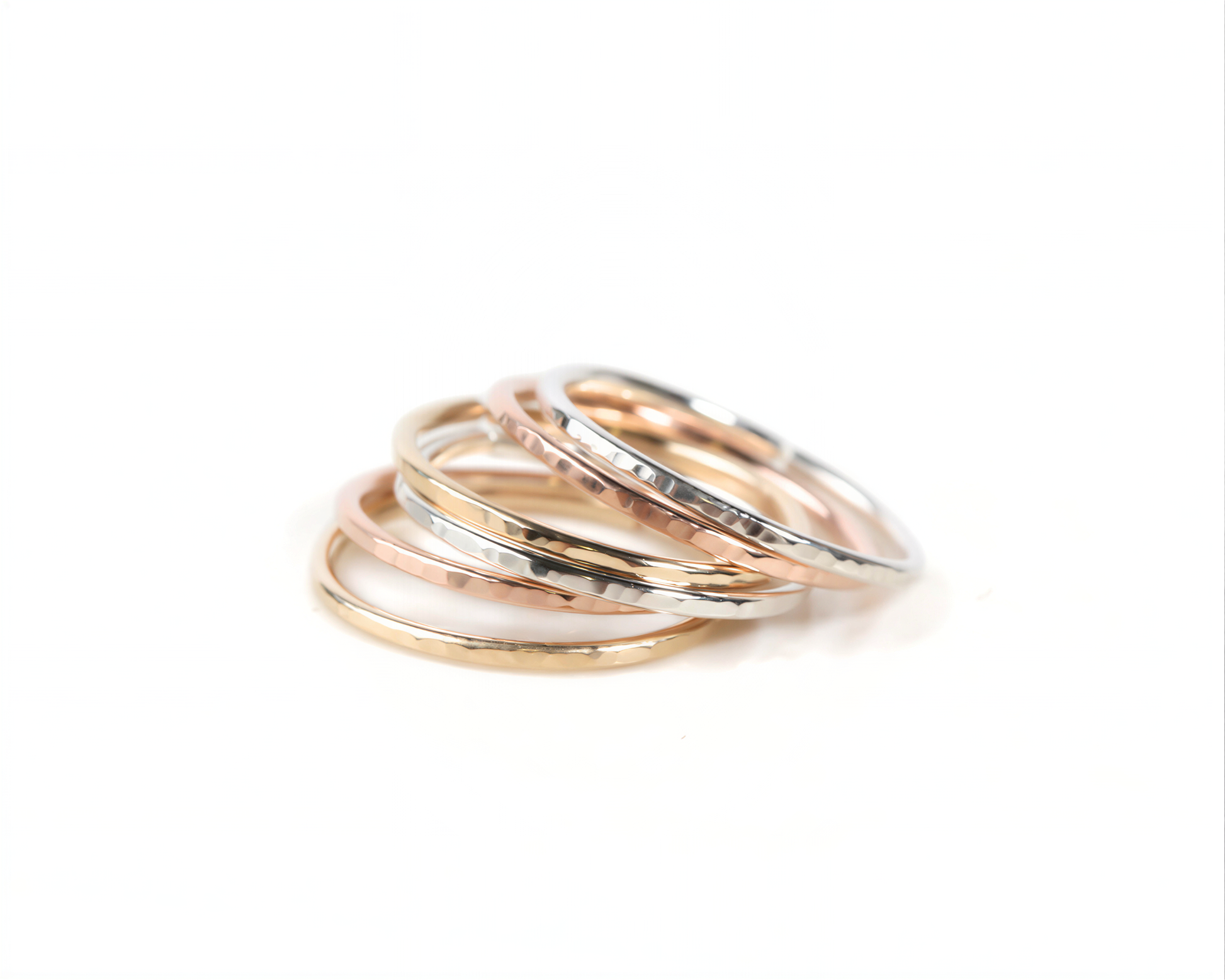 A stack of rings in various colors, including gold, silver, and rose gold, arranged in a visually appealing manner.