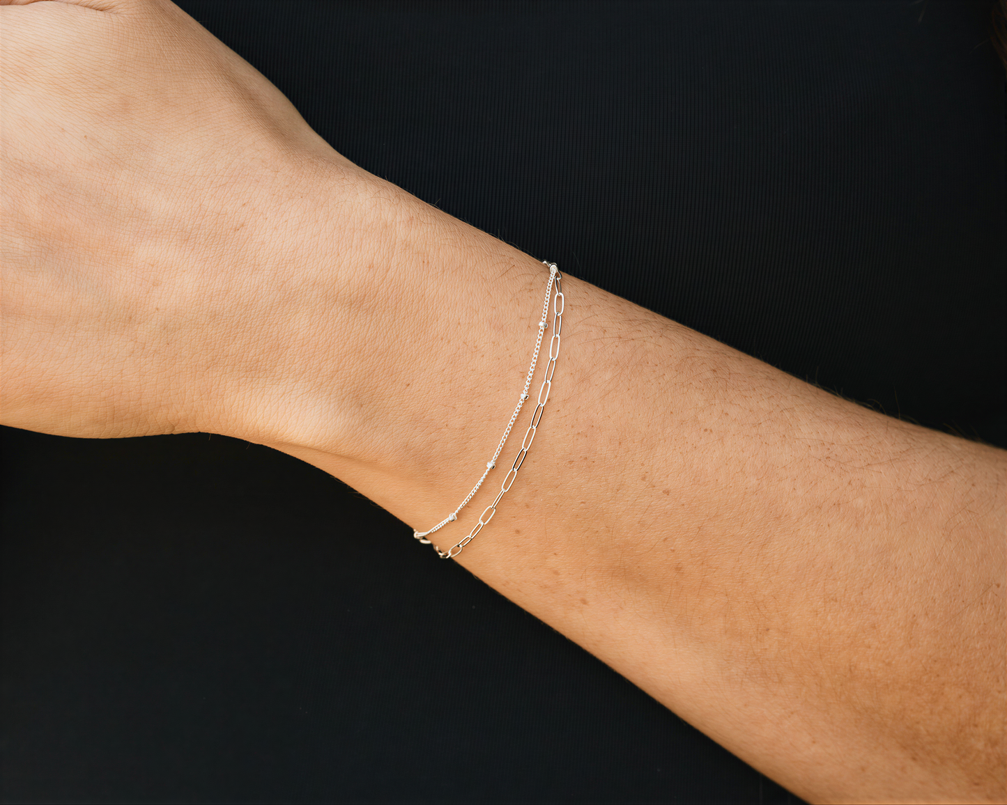 A silver bracelet is worn on a person's wrist.