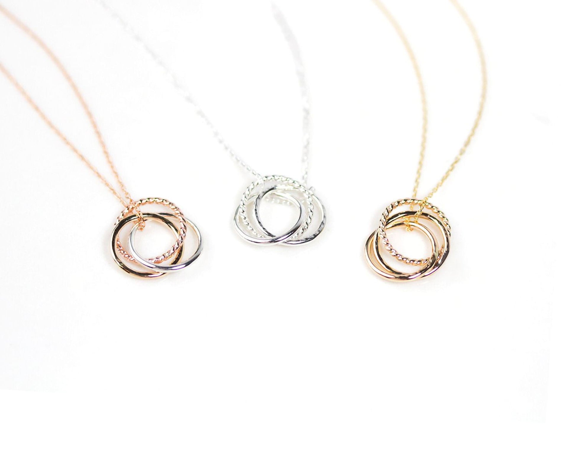 Three necklaces with different colored rings are displayed against a white background.