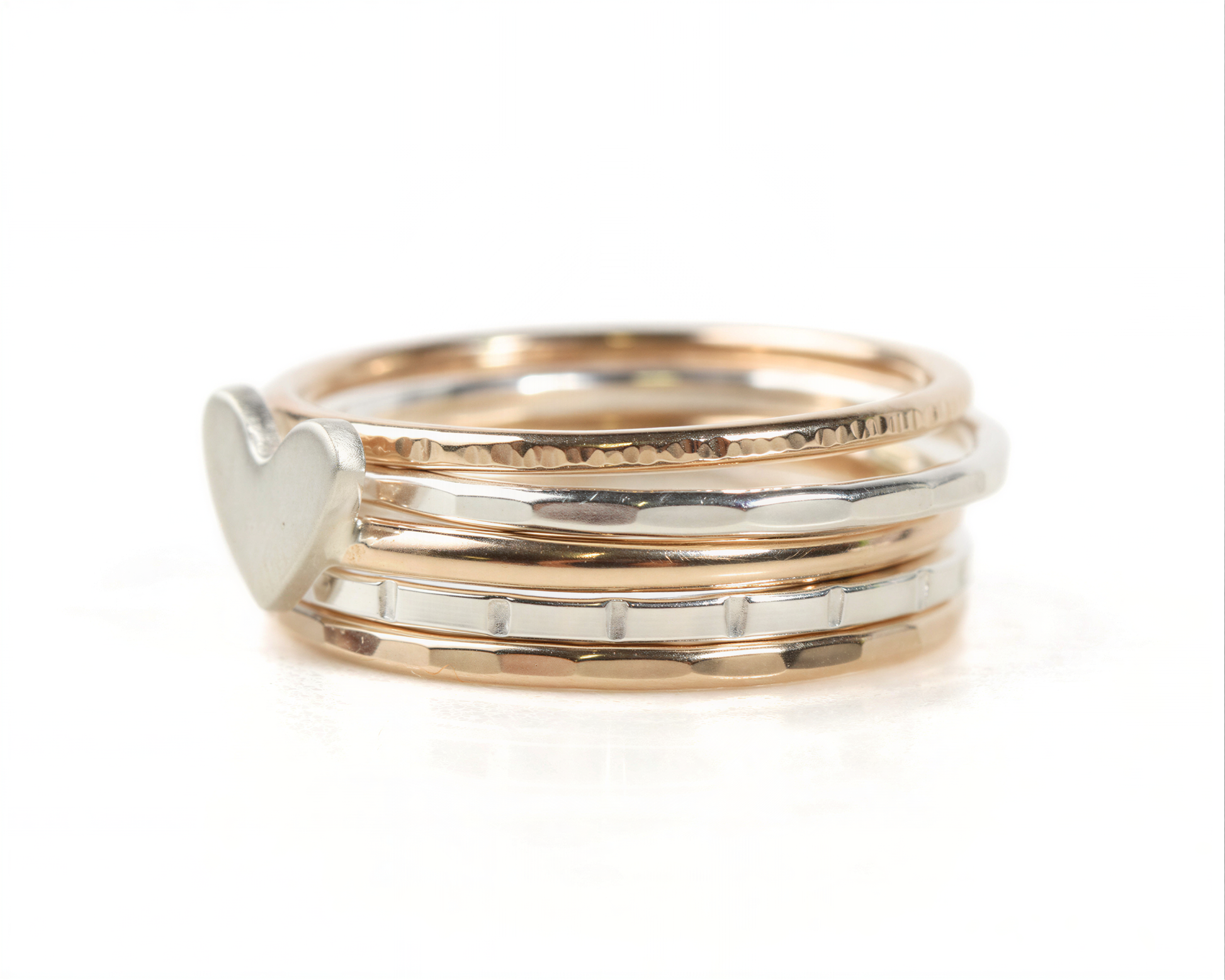 A stack of rings with a heart-shaped charm on the top ring.