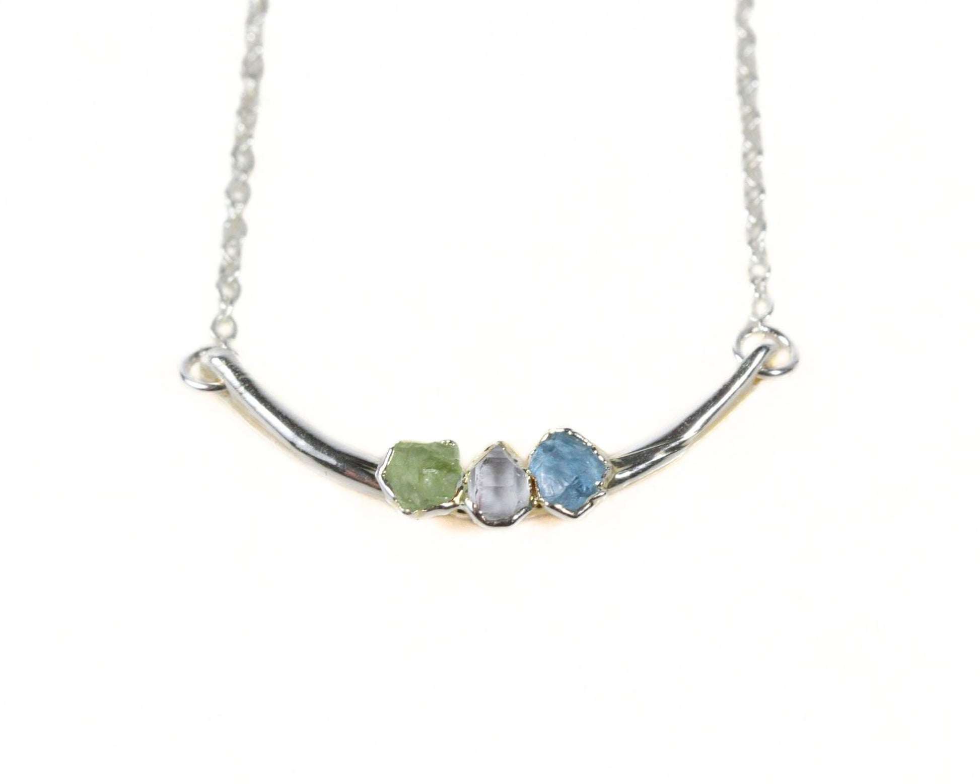 A silver necklace with three gemstones on it.