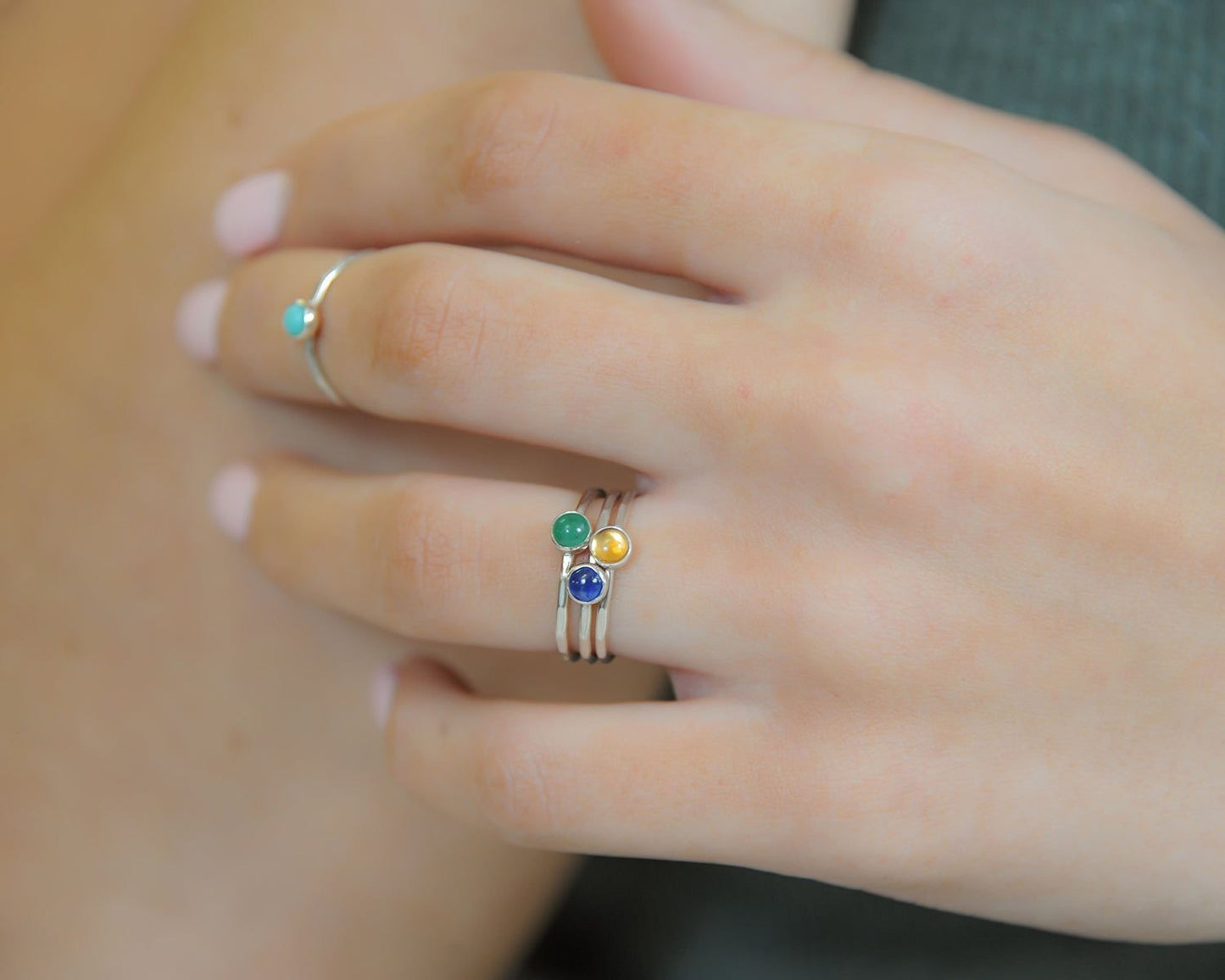 A close-up of a person's hand wearing three rings on the fingers.