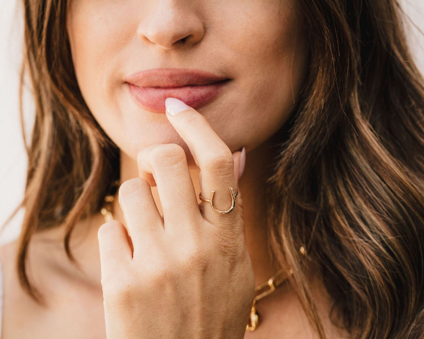 A close-up of a woman's face, focusing on her hand and finger, with a ring on her finger and her lips slightly open.