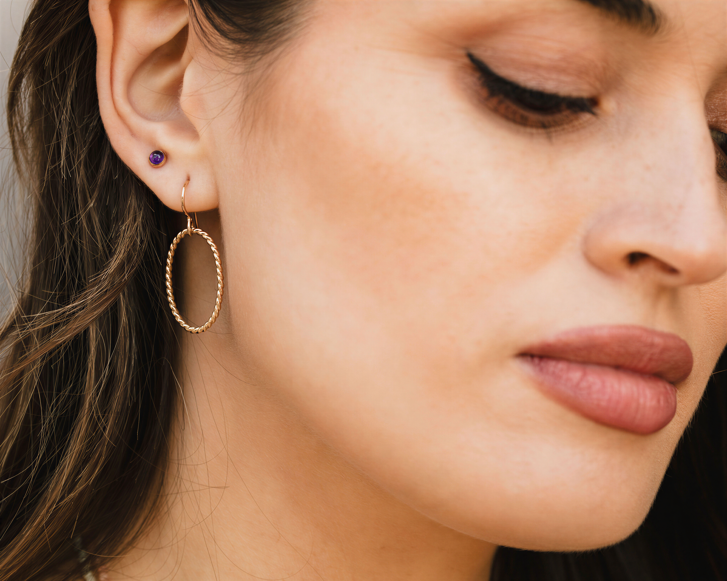 A close-up of a woman's face, focusing on her earrings and lips.