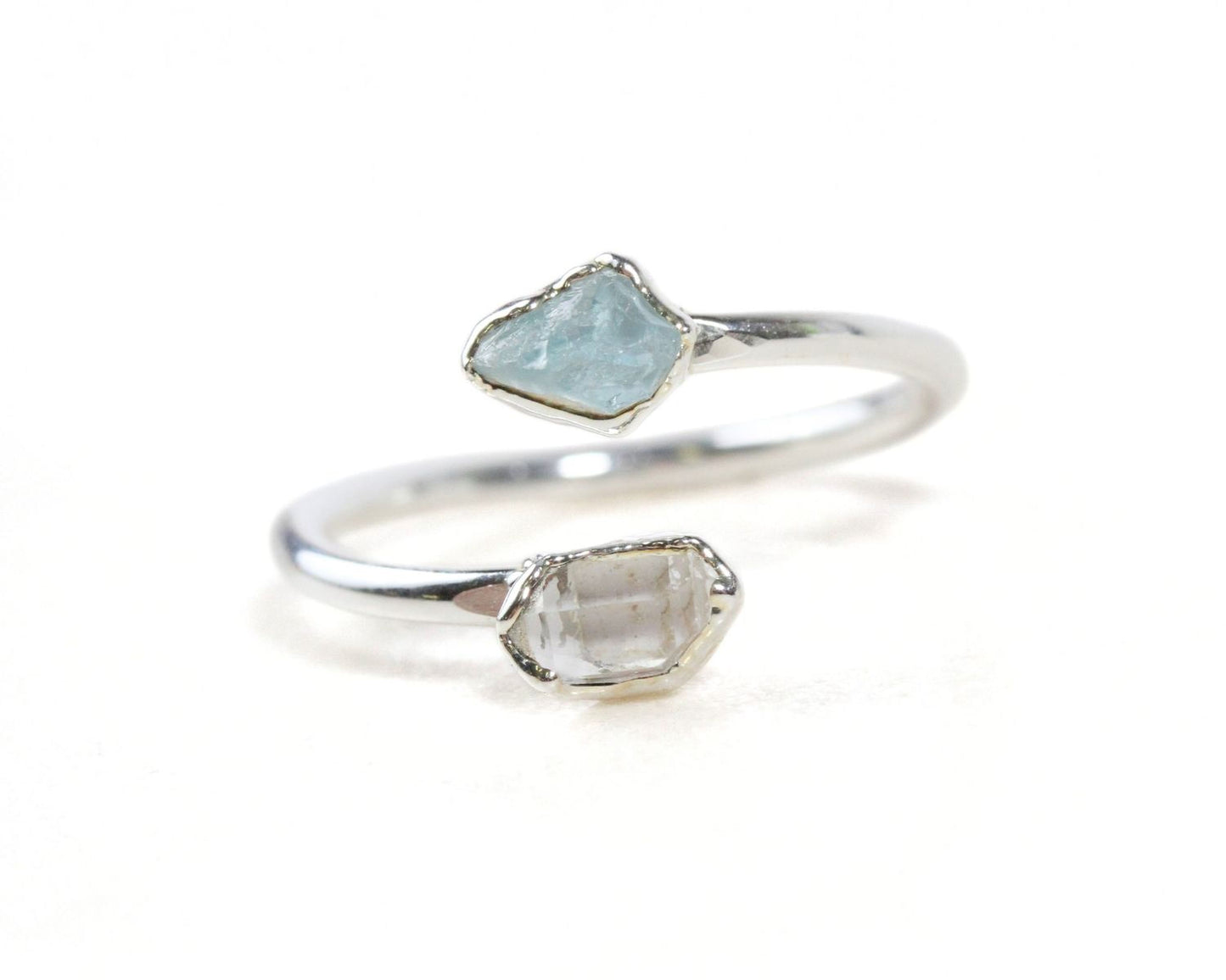 A silver ring with two gemstone stones, one blue and one clear, set in a twisted design.