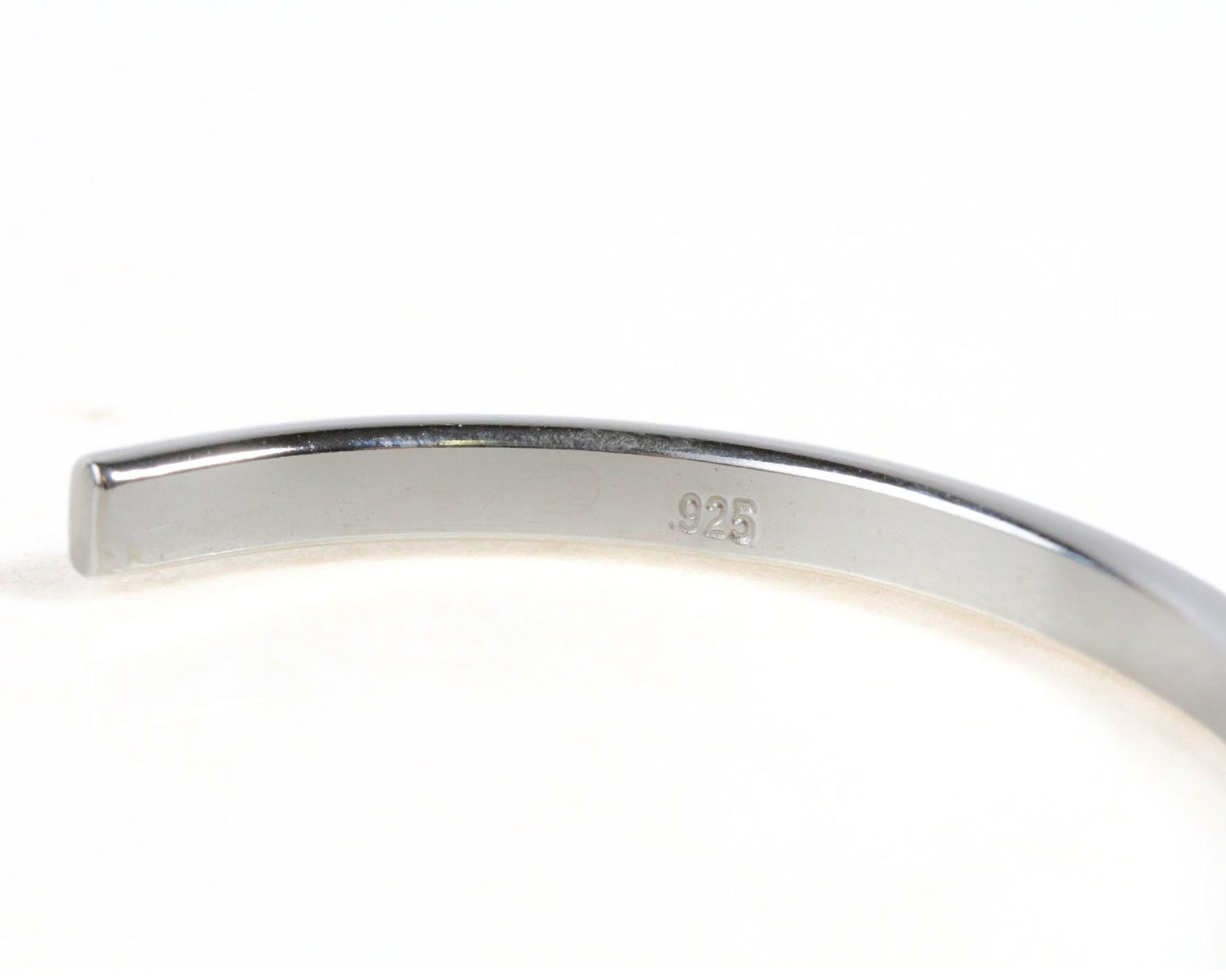 A close-up view of a silver bracelet or bangle, with the number '925' engraved on it.