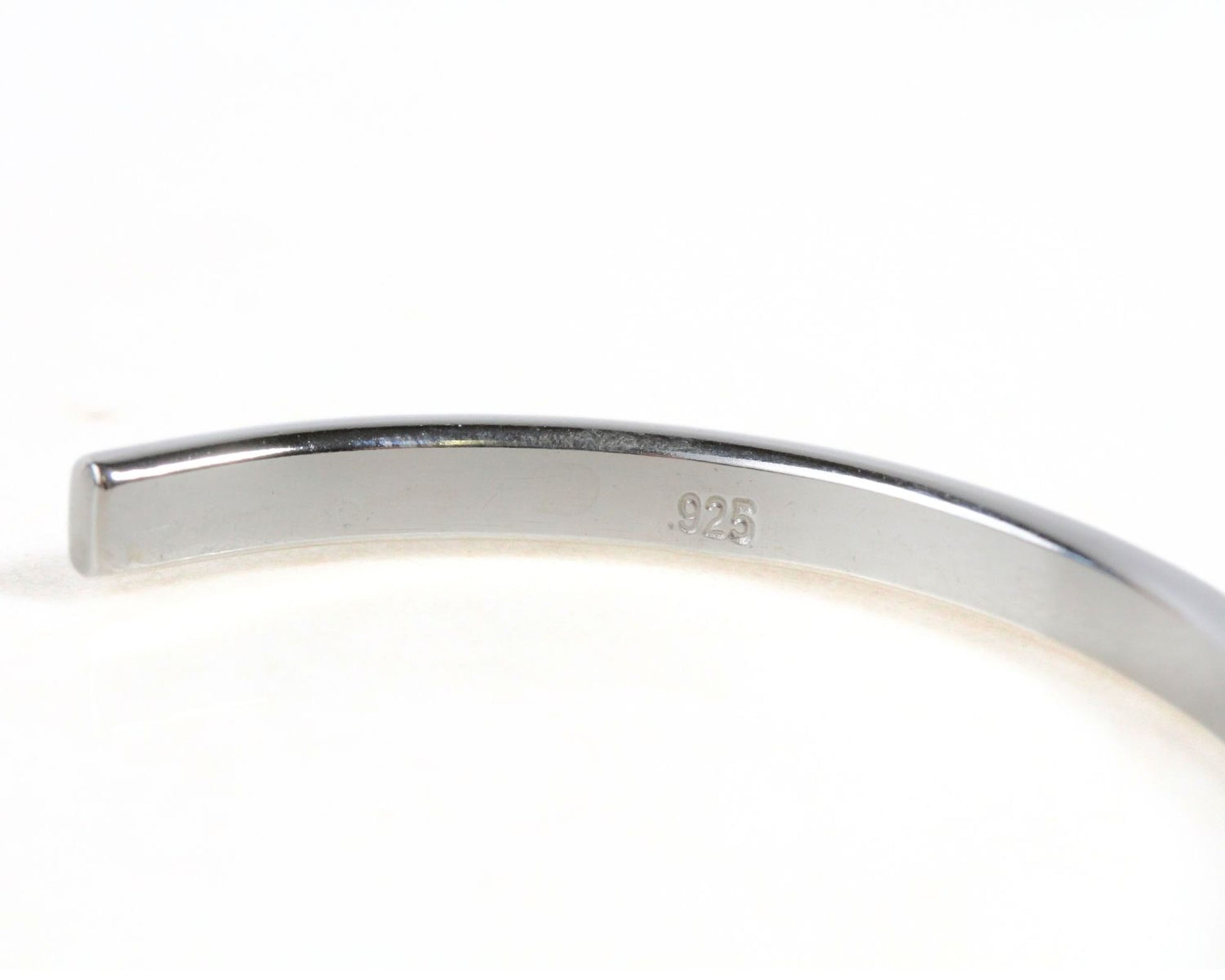 A close-up view of a silver bracelet or bangle, with the number '925' engraved on it.
