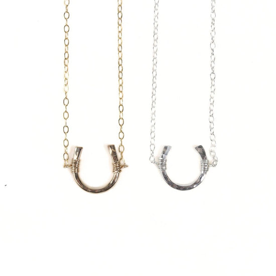 Two necklaces with a horseshoe-shaped pendant are shown against a white background.