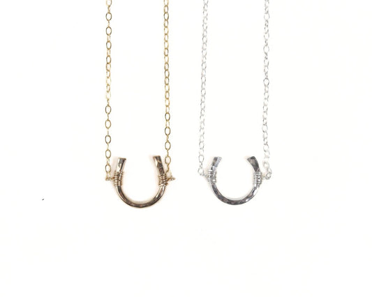 Two necklaces with a horseshoe-shaped pendant are shown against a white background.