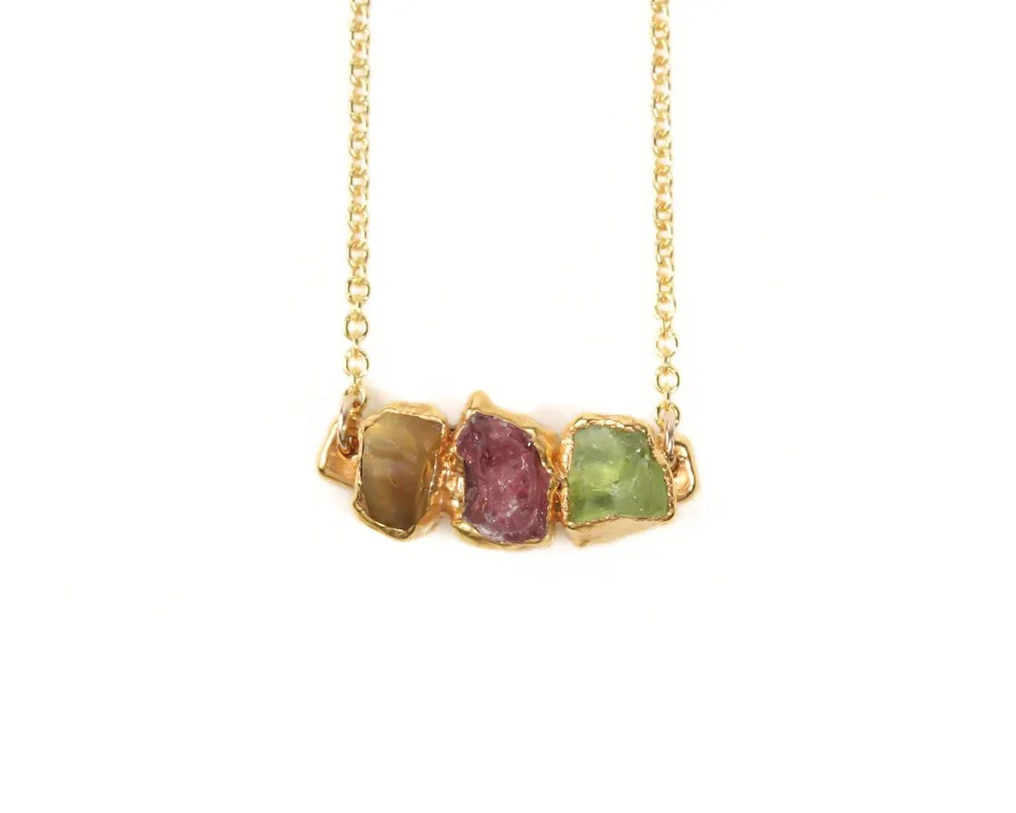 A gold necklace with three gemstones on it.