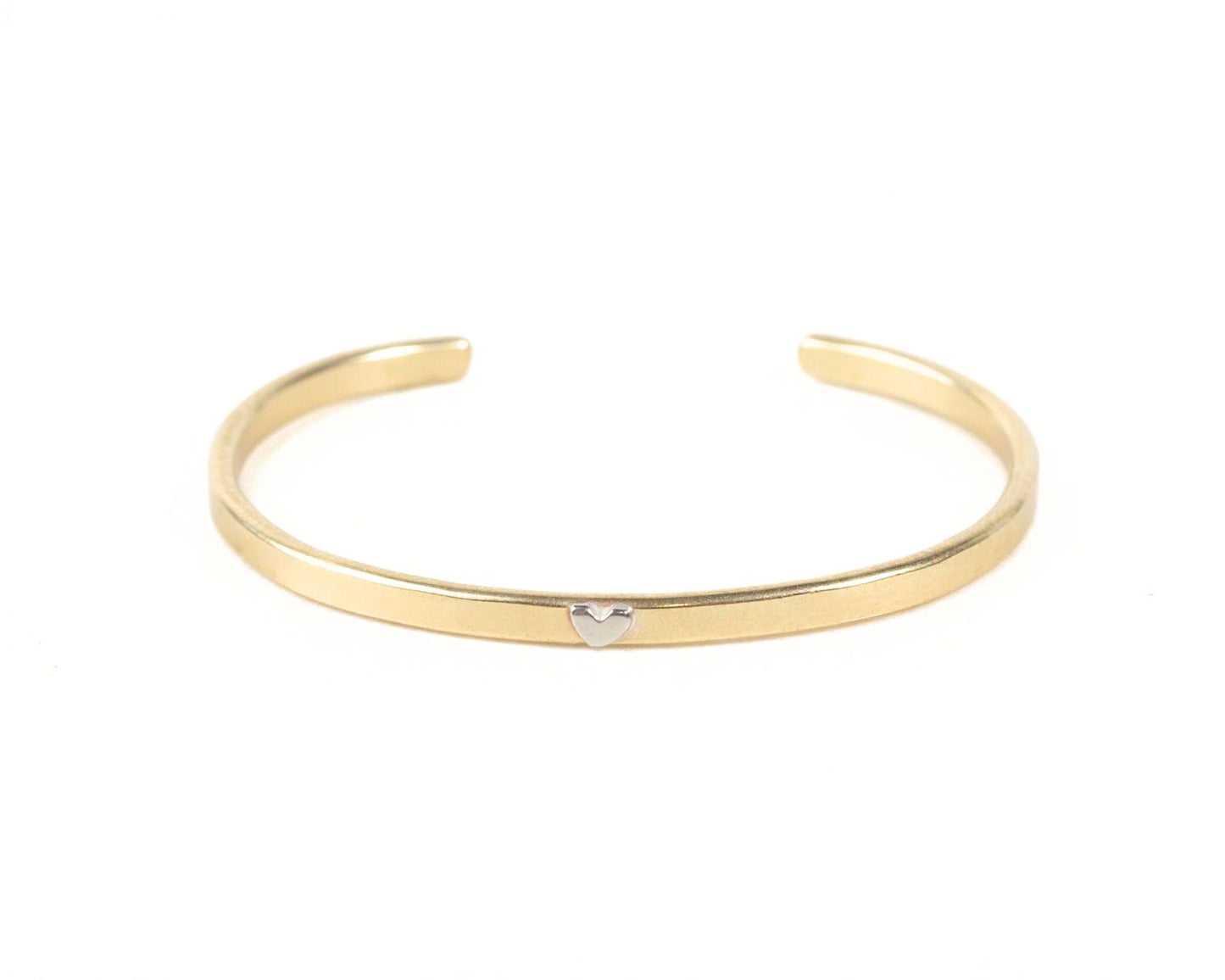 A gold-colored bracelet with a heart-shaped charm on it.