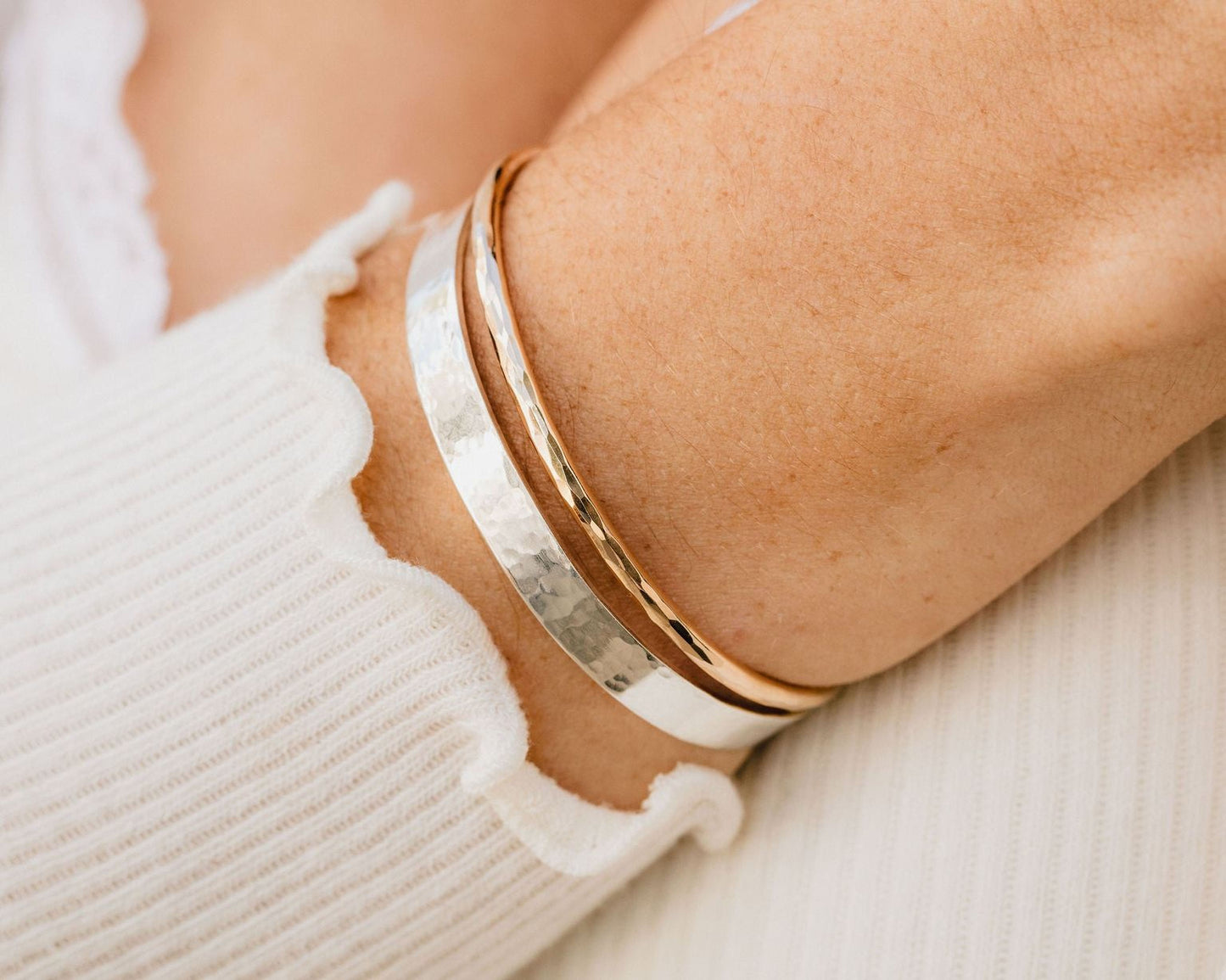 A close-up view of a person's arm wearing a silver and gold bracelet.