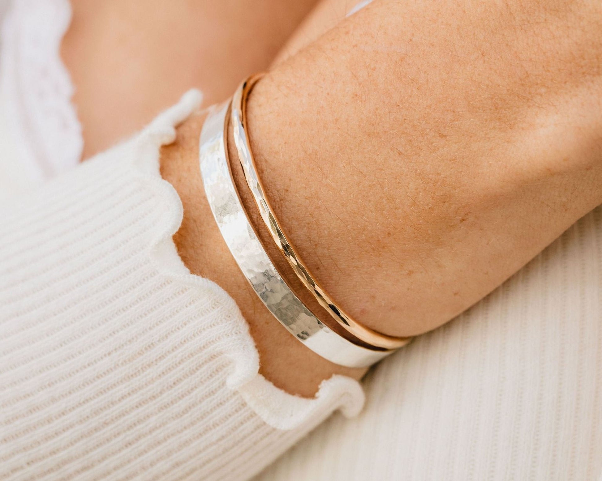 A close-up view of a person's arm wearing a silver and gold bracelet.