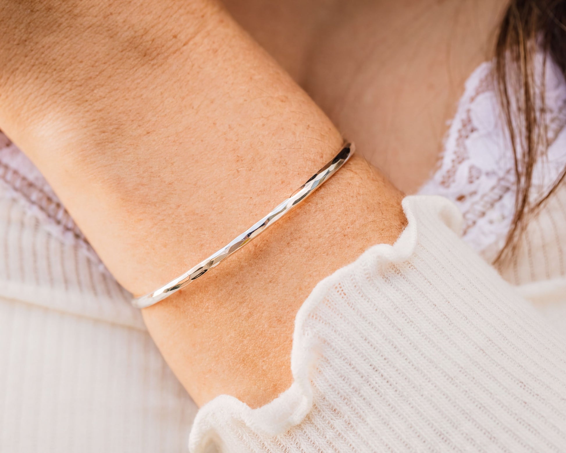 A close-up view of a person's arm wearing a silver bracelet.