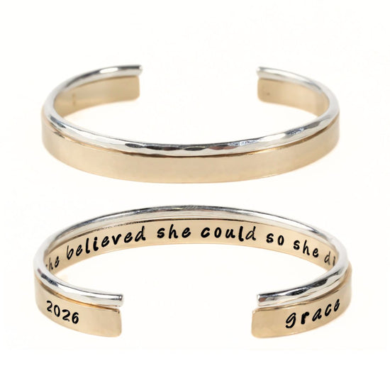 A gold-colored bracelet with a text engraved on it.
