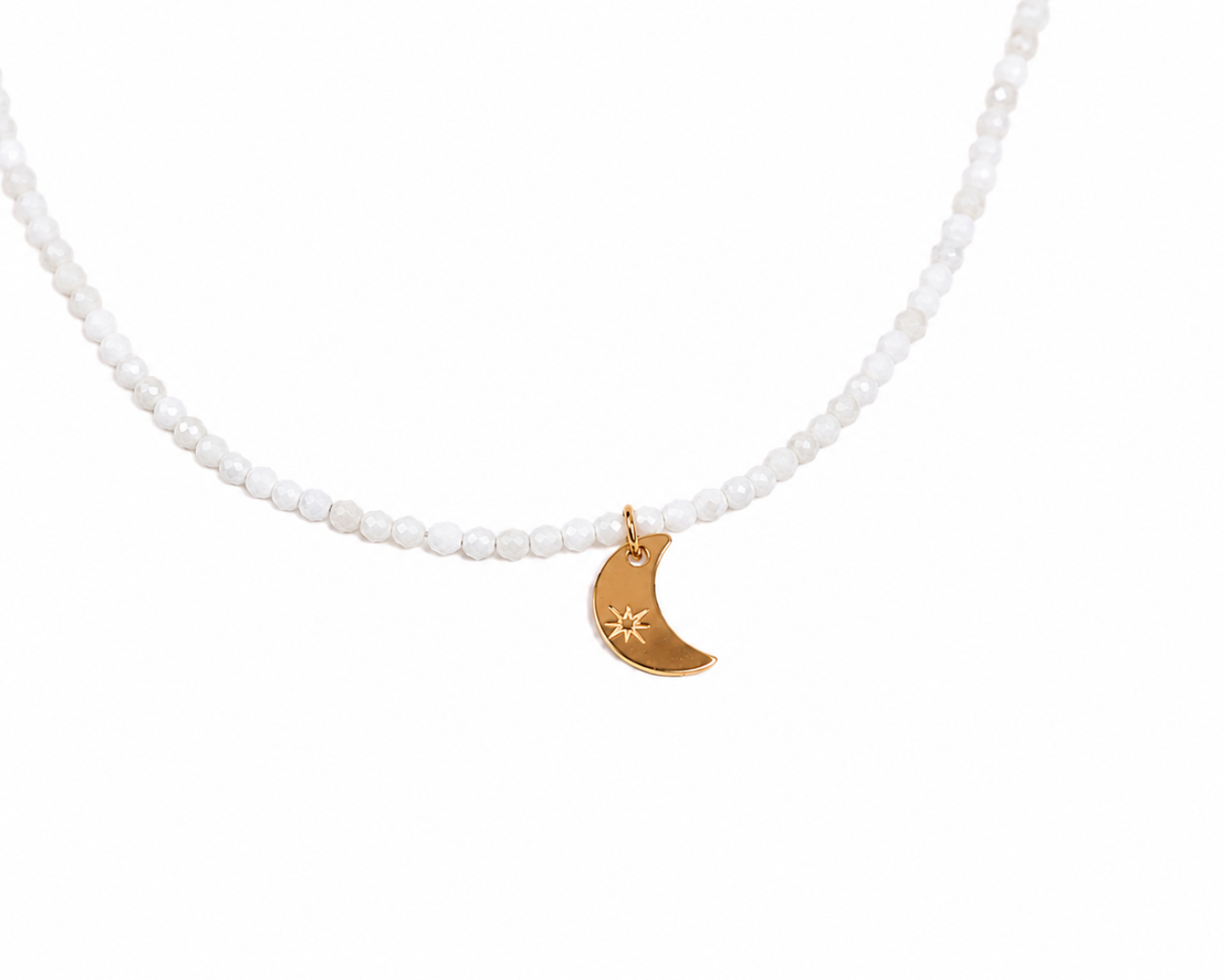 A necklace with white beads and a gold-colored charm in the shape of a crescent moon.