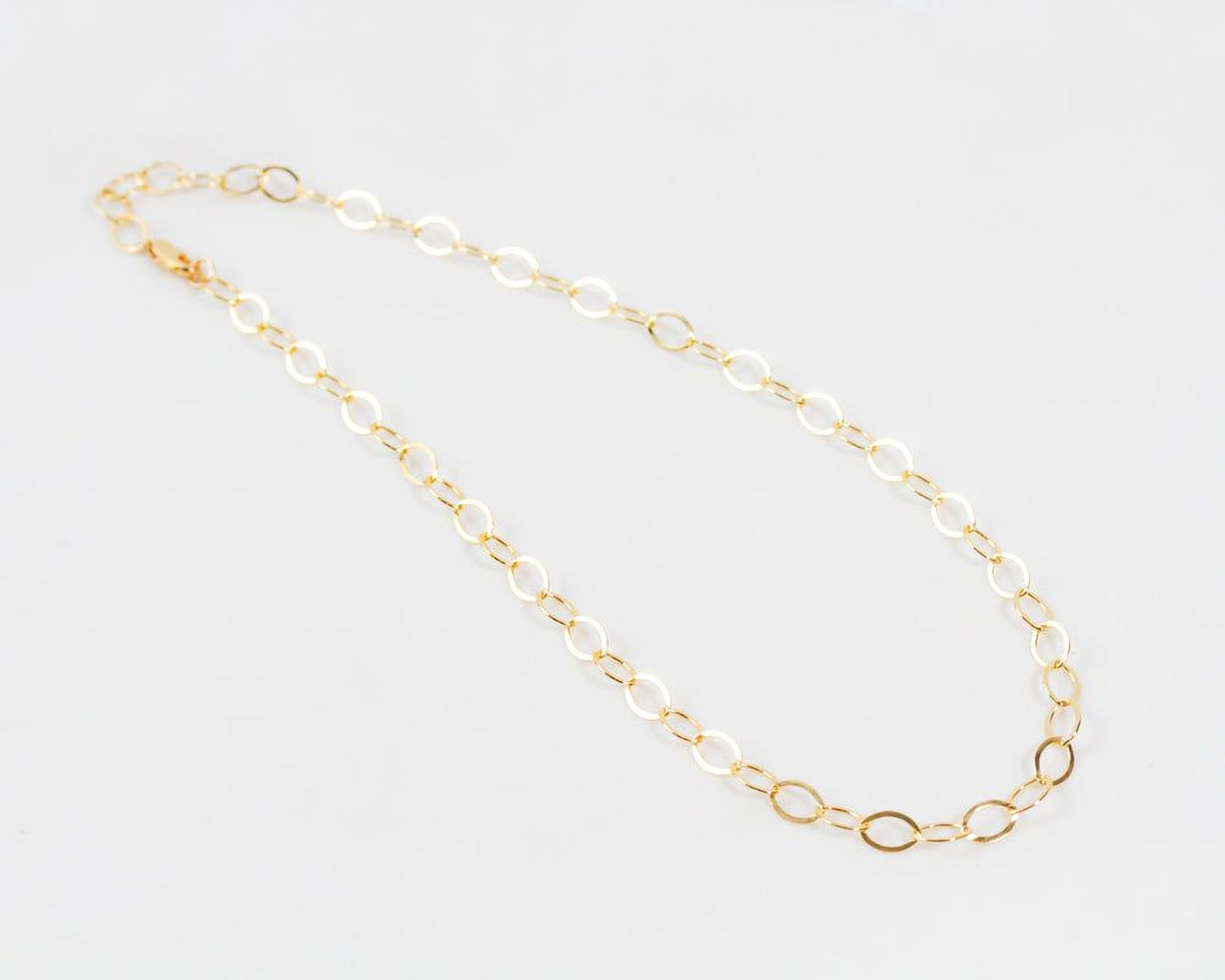 Image shows close up of our exquisite 14 karat Gold Filled Oval Link Chain Necklace. Create a super chic look for all occasions and ensembles. Each 8X6 oval link glints and gleams. Wear it long or short and make a statement. Great layering necklace
