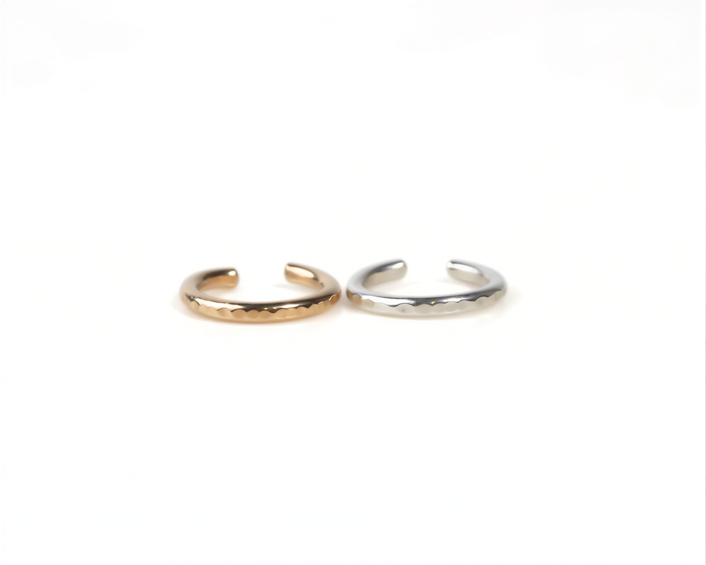 Two rings, one gold and one silver, are placed side by side on a white background.