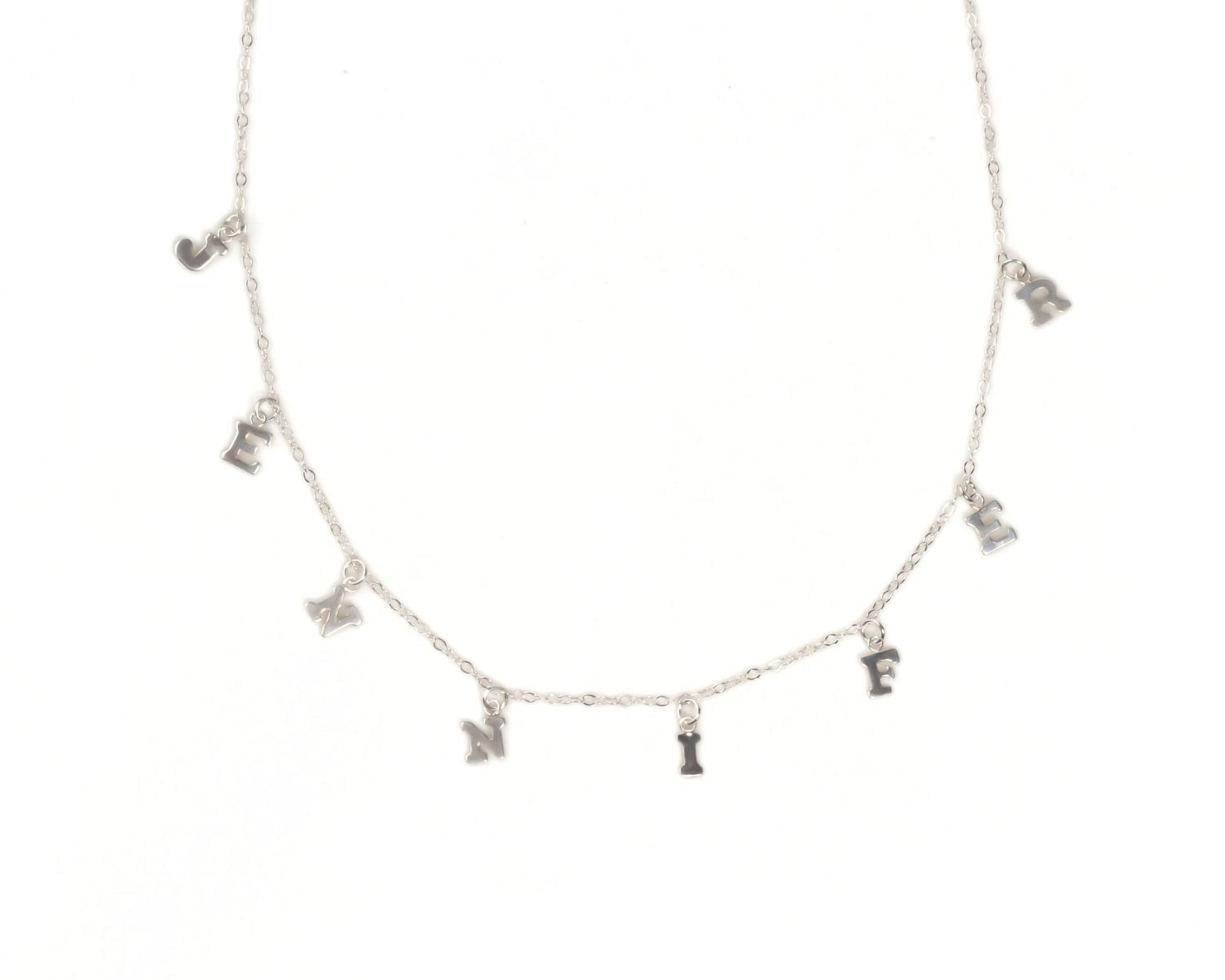 A necklace with a series of small silver charms hanging from it, each containing a letter of the alphabet.