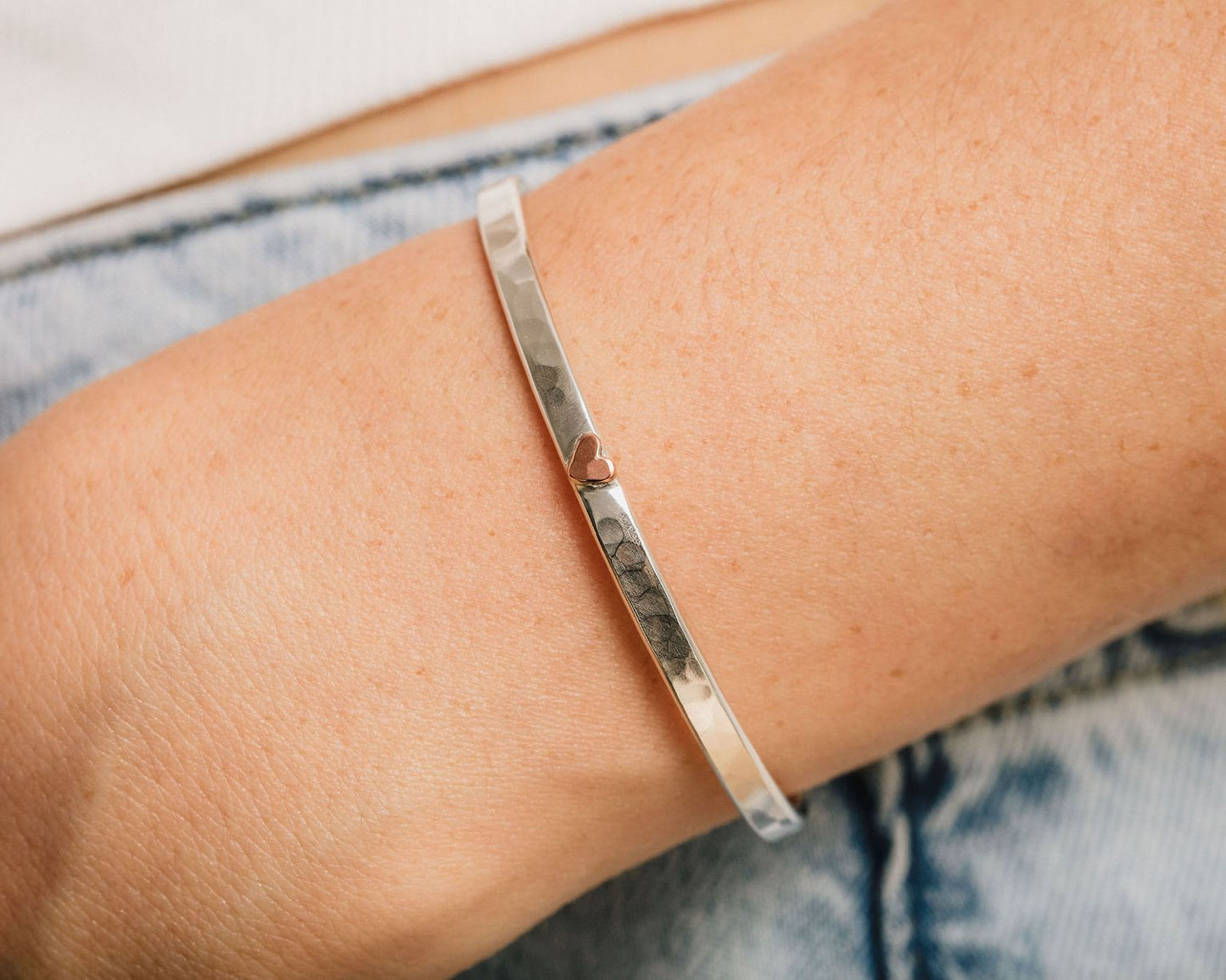 A silver bangle bracelet is worn on a person's wrist.