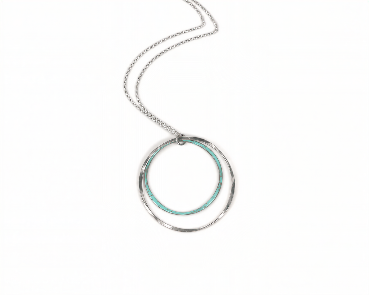 A silver necklace with a circular pendant featuring two concentric rings of turquoise-colored metal.