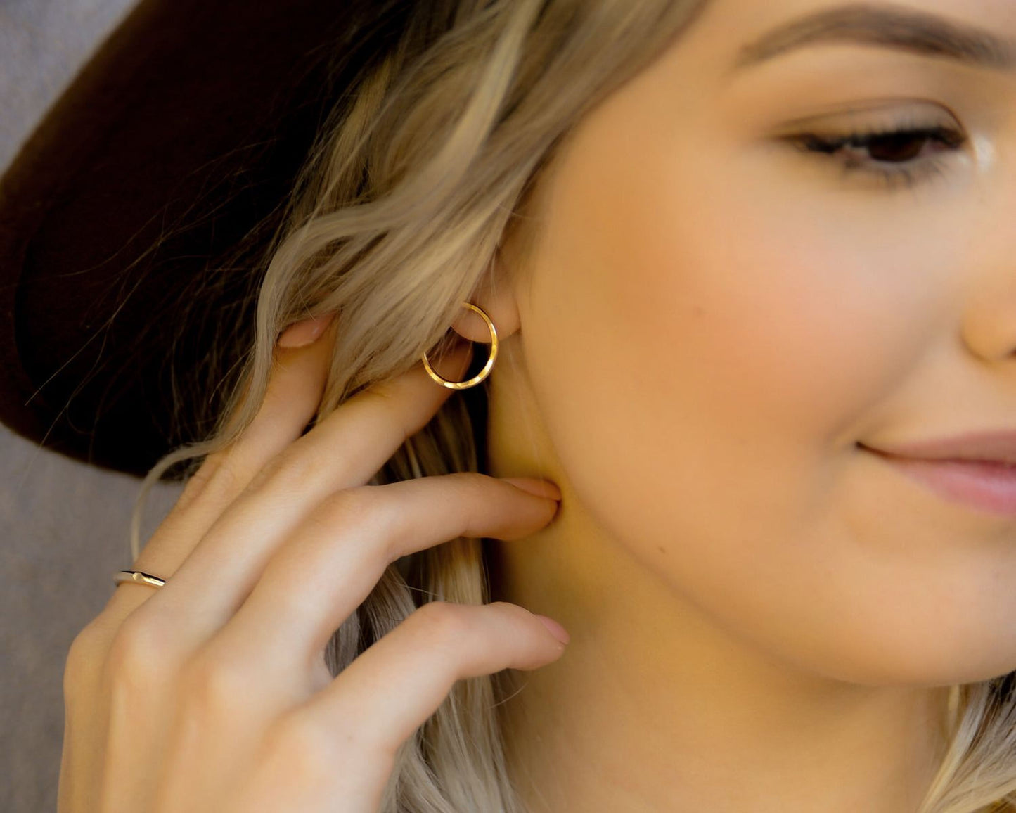 A close-up of a woman's face, focusing on her earrings and hand.