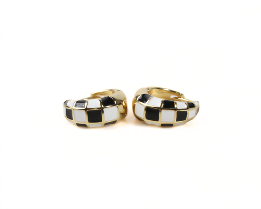 A pair of gold hoop earrings with a black and white checkered pattern.