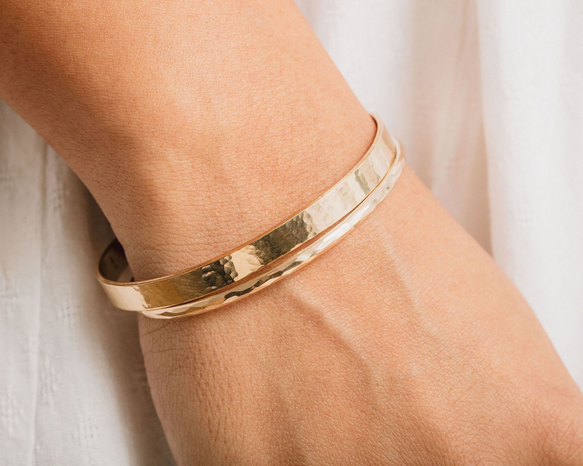 A gold-colored bracelet is worn on a person's wrist.