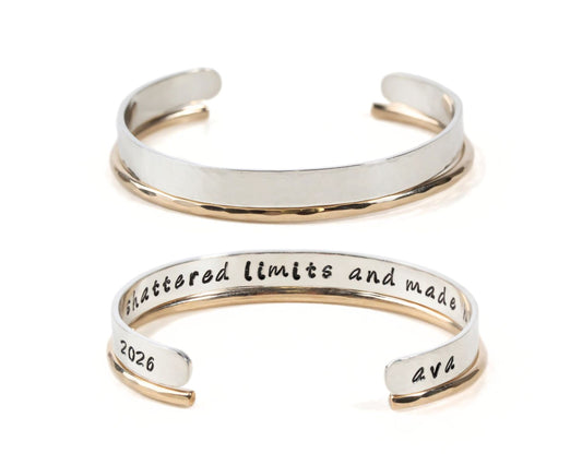 a silver and gold bracelet with the engraved inscription " shattered limits and made" on it.