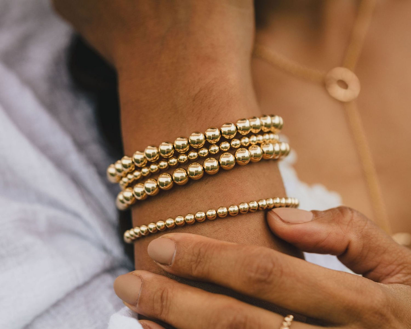 A close-up view of a person's wrist adorned with multiple gold-colored beaded bracelets.