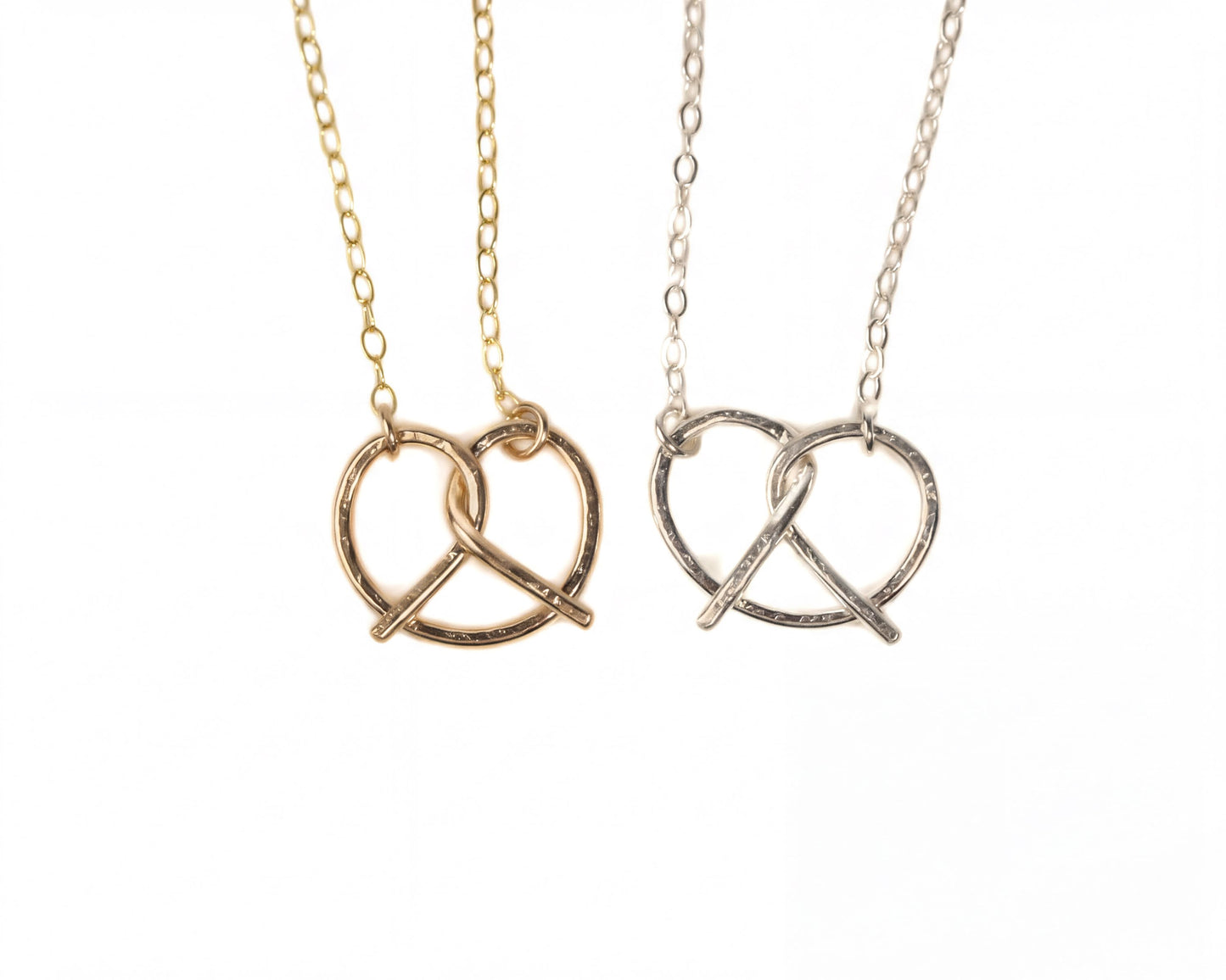 Two necklaces with pendant designs, one in gold and one in silver, both featuring a heart-shaped pendant.
