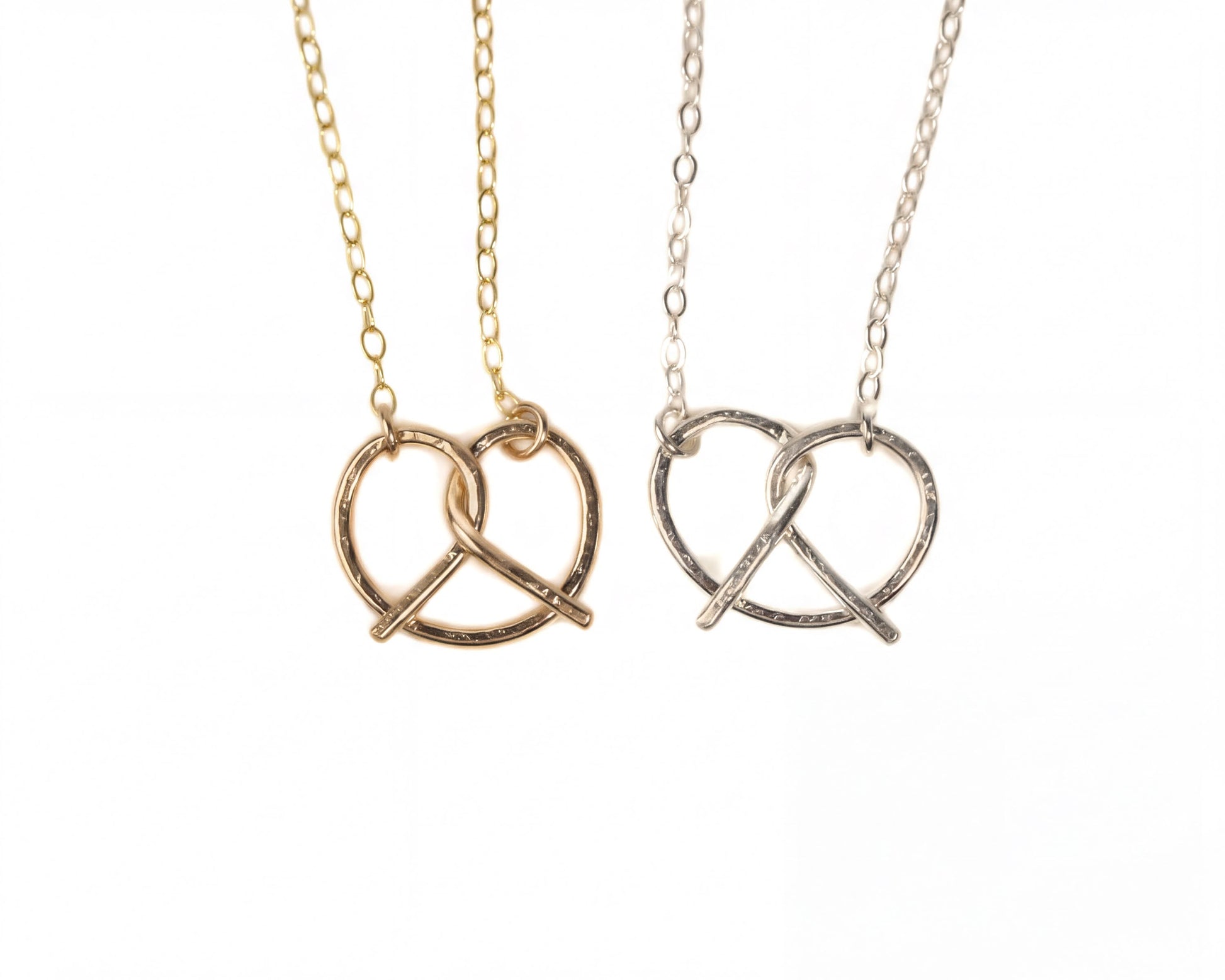 Two necklaces with pendant designs, one in gold and one in silver, both featuring a heart-shaped pendant.