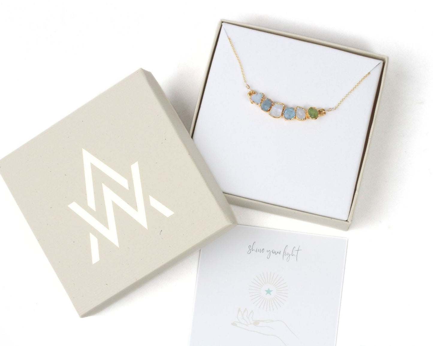 a necklace in a box with a note and a card underneath it.
