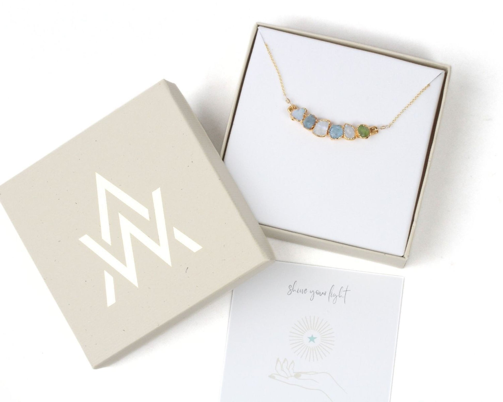 a necklace in a box with a note and a card underneath it.
