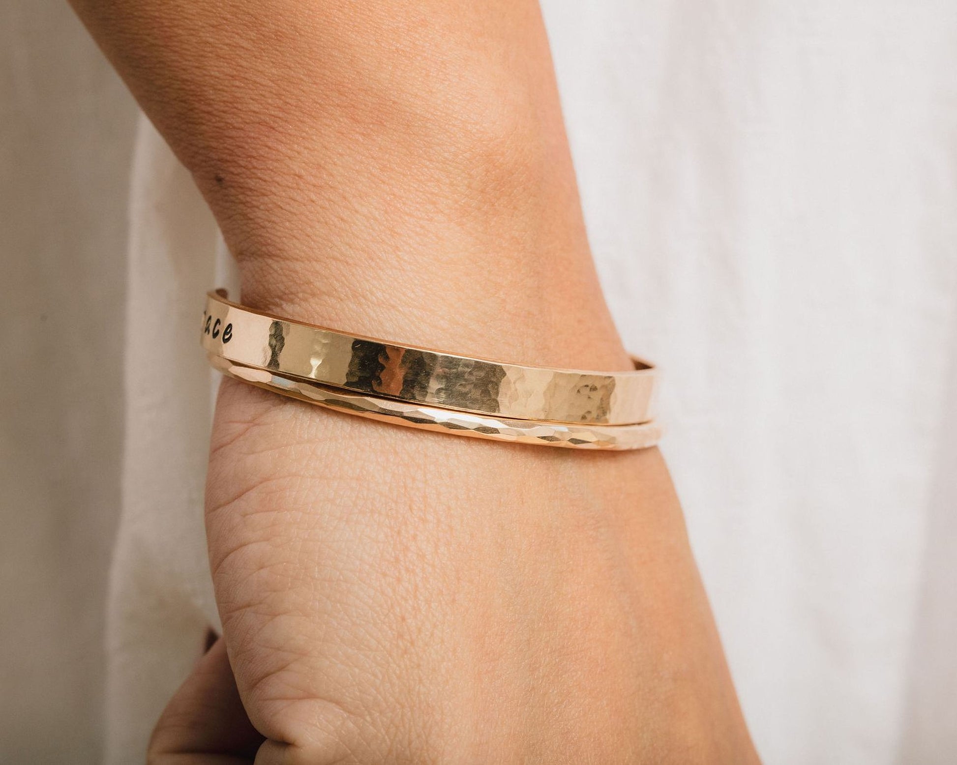 A gold-colored bracelet is worn on a person's wrist.