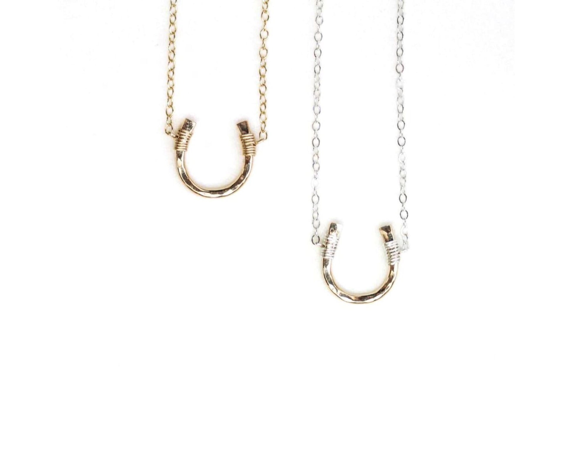 two necklaces with a unique design, each featuring a curved metal piece that resembles a horseshoe or a small horseshoe-shaped pendant.