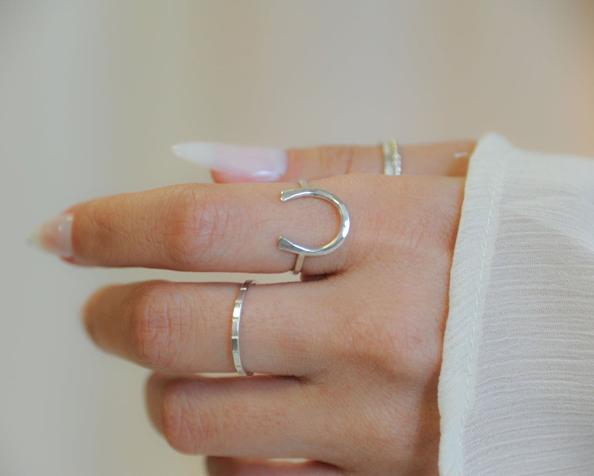 A close-up of a person's hand wearing multiple rings on the fingers.