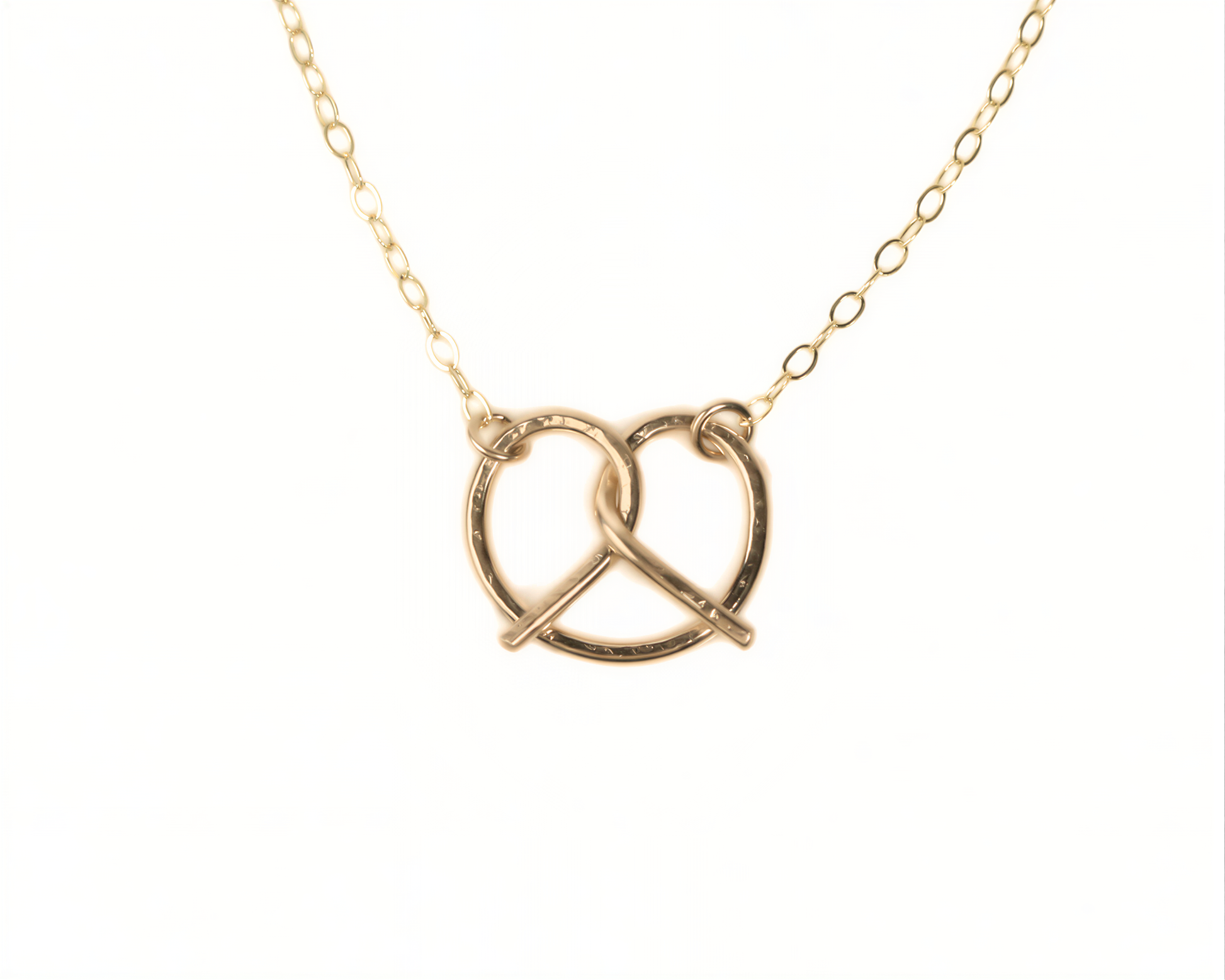 A delicate gold necklace with a heart-shaped pendant in the center.